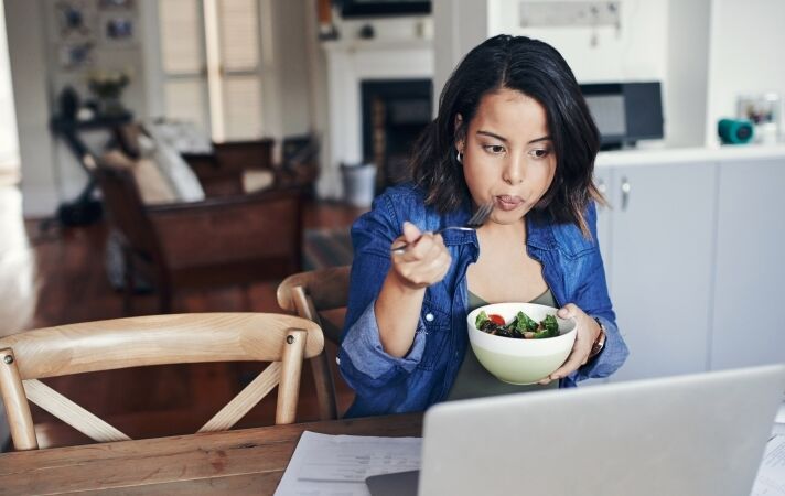 Young woman eating at desk laptop 800 450