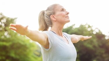 Midlife woman doing yoga stretch in park