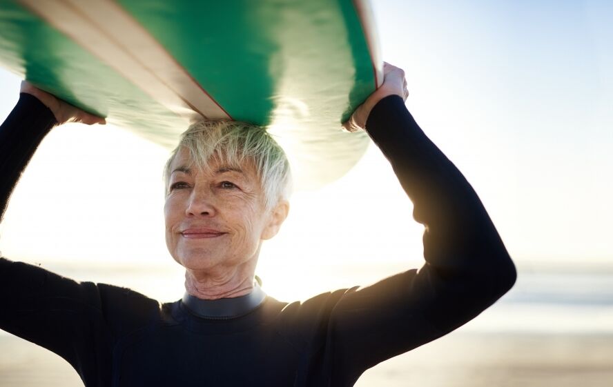 Older woman surfing surfboard beach sun summer 999 561