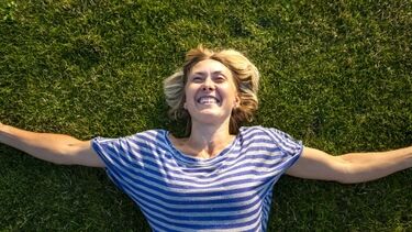 Woman lying on grass happy 450 253