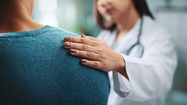 A doctor placing their hand on a patients shoulder