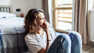 A woman sitting on the floor in her bedroom
