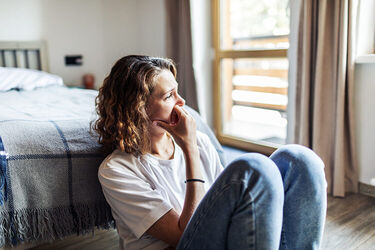 A woman sitting on the floor in her bedroom