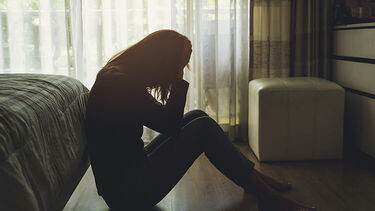 A woman sitting in the dark with her head in her hands
