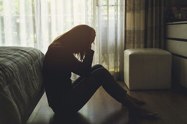 A woman sitting in the dark with her head in her hands