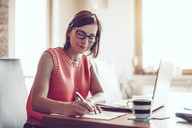 Female health professional working on laptop & notepad