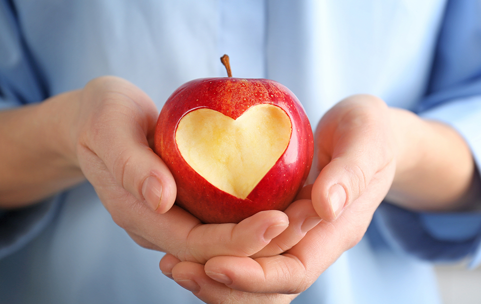Woman holding apple with heart in hands