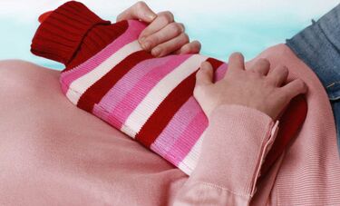 woman with stomach pain holding hot water bottle