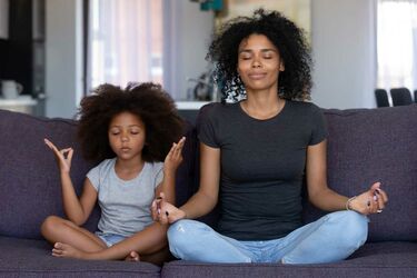 African mum with daughter meditating