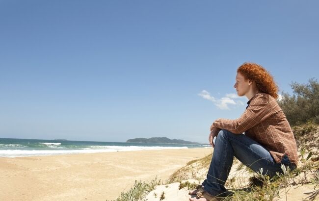 Young woman at beach alone looking at ocean 650 433