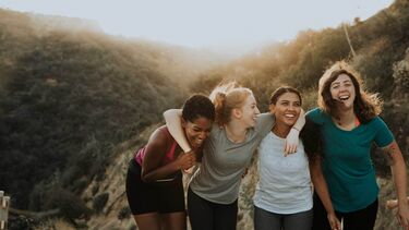 Young women on hike laughing hugging