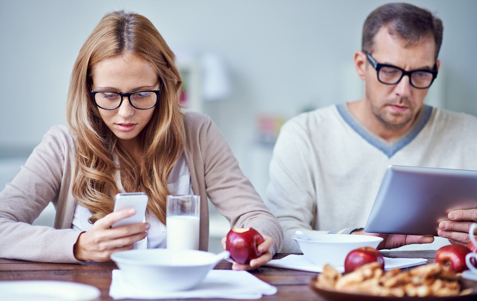 Couple using iphones at breakfast table