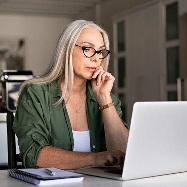 Focused older woman using laptop