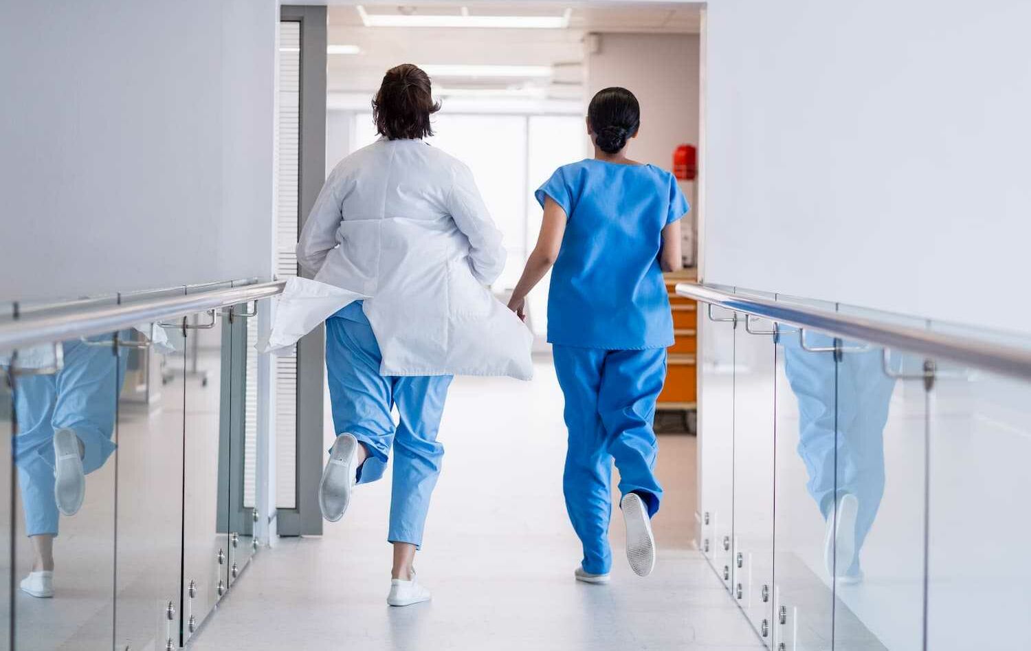 Rear view of nurse and doctor running in hospital corridor 1